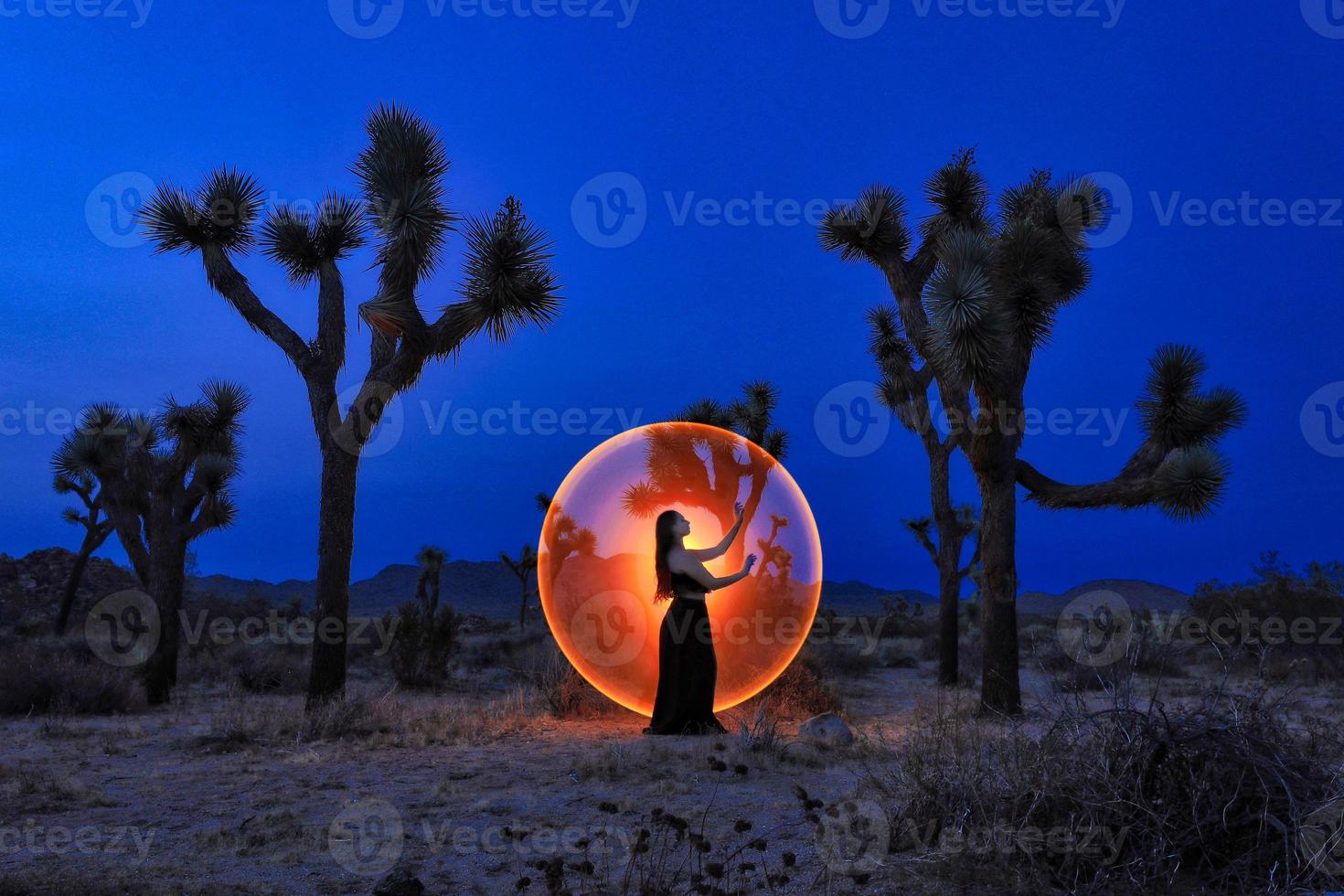posa di una ragazza dipinta di luce negli alberi del deserto di Joshua Tree foto