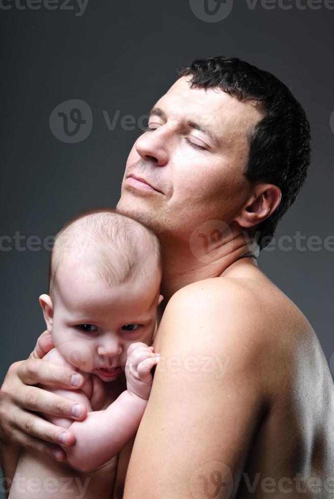 giovane uomo felice che tiene un bambino di 4-5 mesi in studio foto