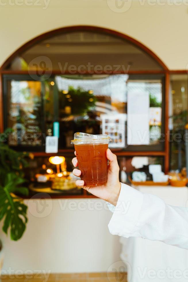 mano che tiene un bicchiere di caffè americano ghiacciato foto