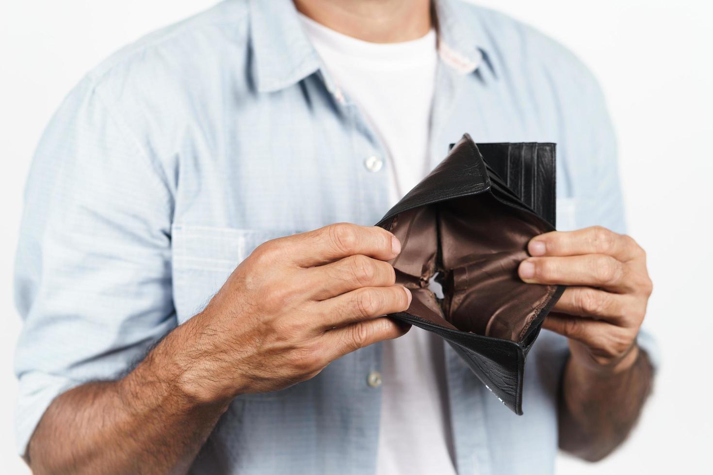 uomo maturo sconvolto che tiene il suo portafoglio vuoto su sfondo bianco. crisi finanziaria, fallimento, niente soldi, cattivo concetto di economia. foto