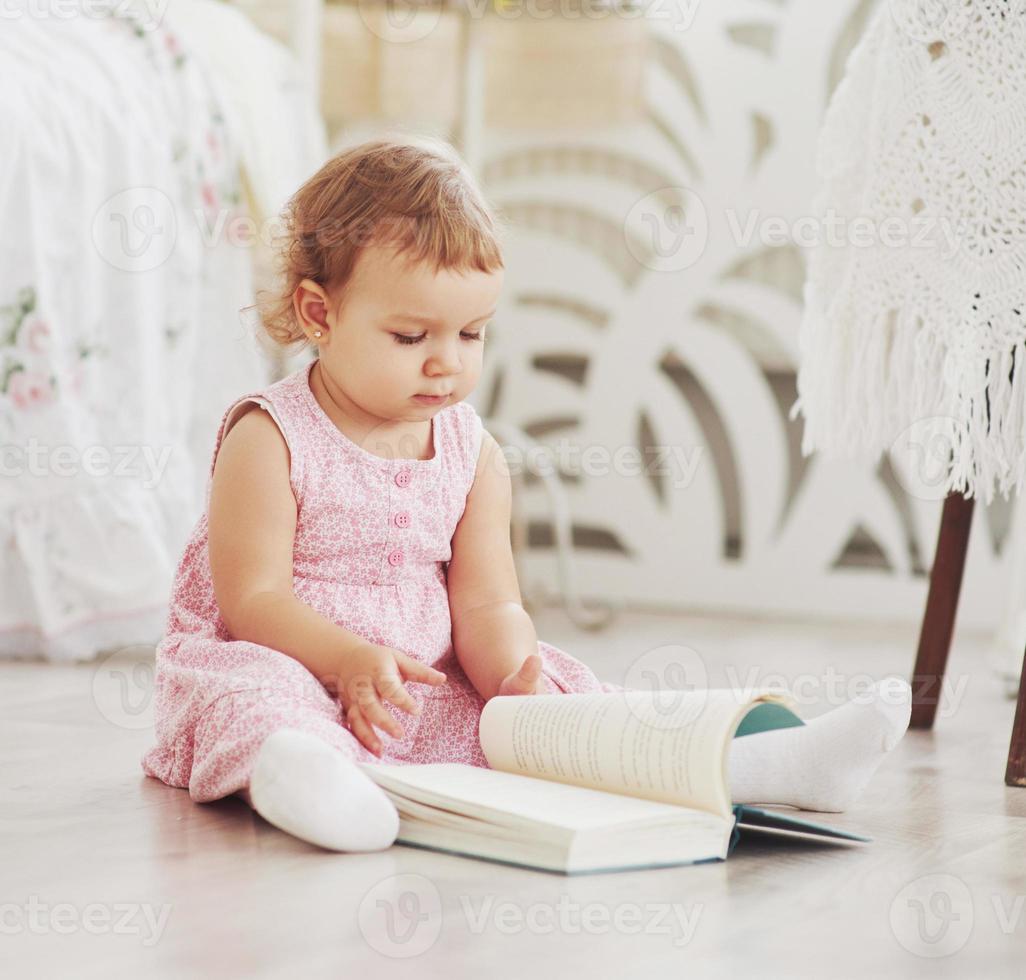 la bellissima bambina legge un libro con il suo orsetto preferito su una morbida coperta di peluche foto