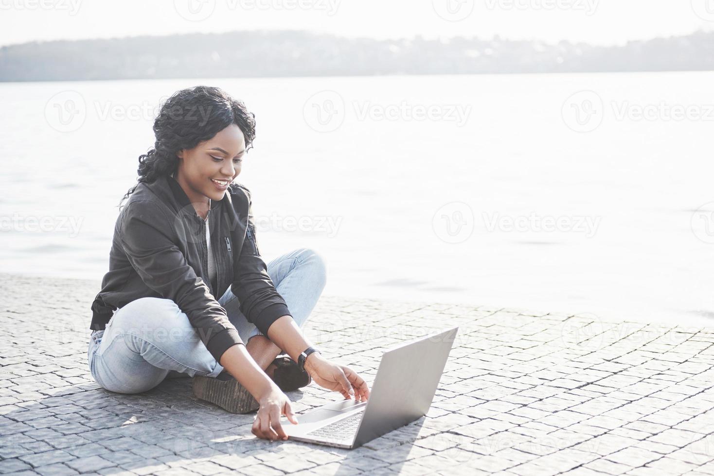 giovane donna per strada che lavora al laptop foto