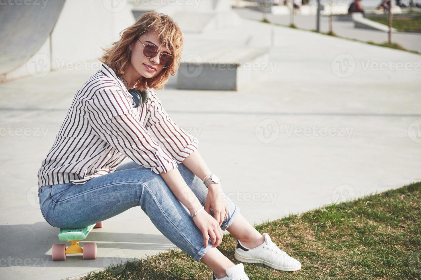 una bella ragazza si sta divertendo nel parco e cavalca uno skateboard foto