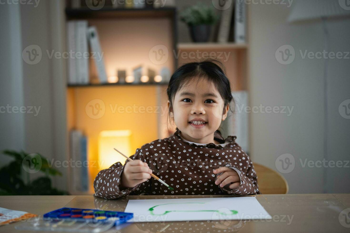 carino poco asiatico bambino sorridente pittura con colorato vernici utilizzando acquerello. asiatico ragazza utilizzando pennello disegno colore. bambino attività stile di vita concetto. foto