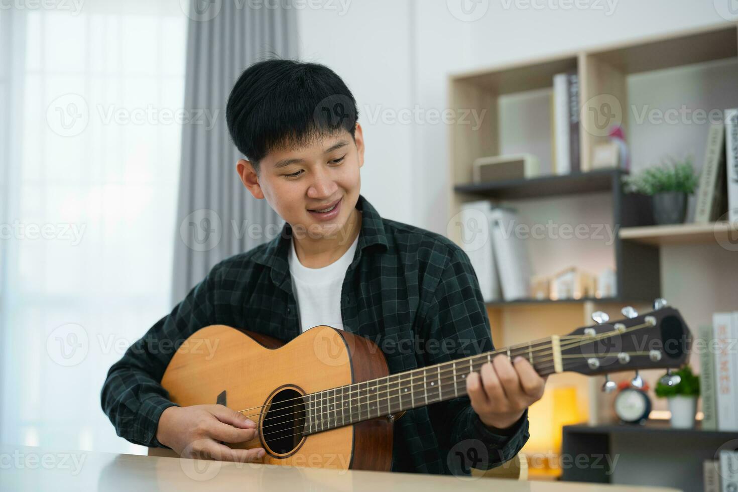 uomo asiatico youtuber spettacolo di live streaming che suona la chitarra e canta una canzone. uomo asiatico che insegna chitarra e canta online. musicista che registra musica con il laptop e suona la chitarra acustica. foto