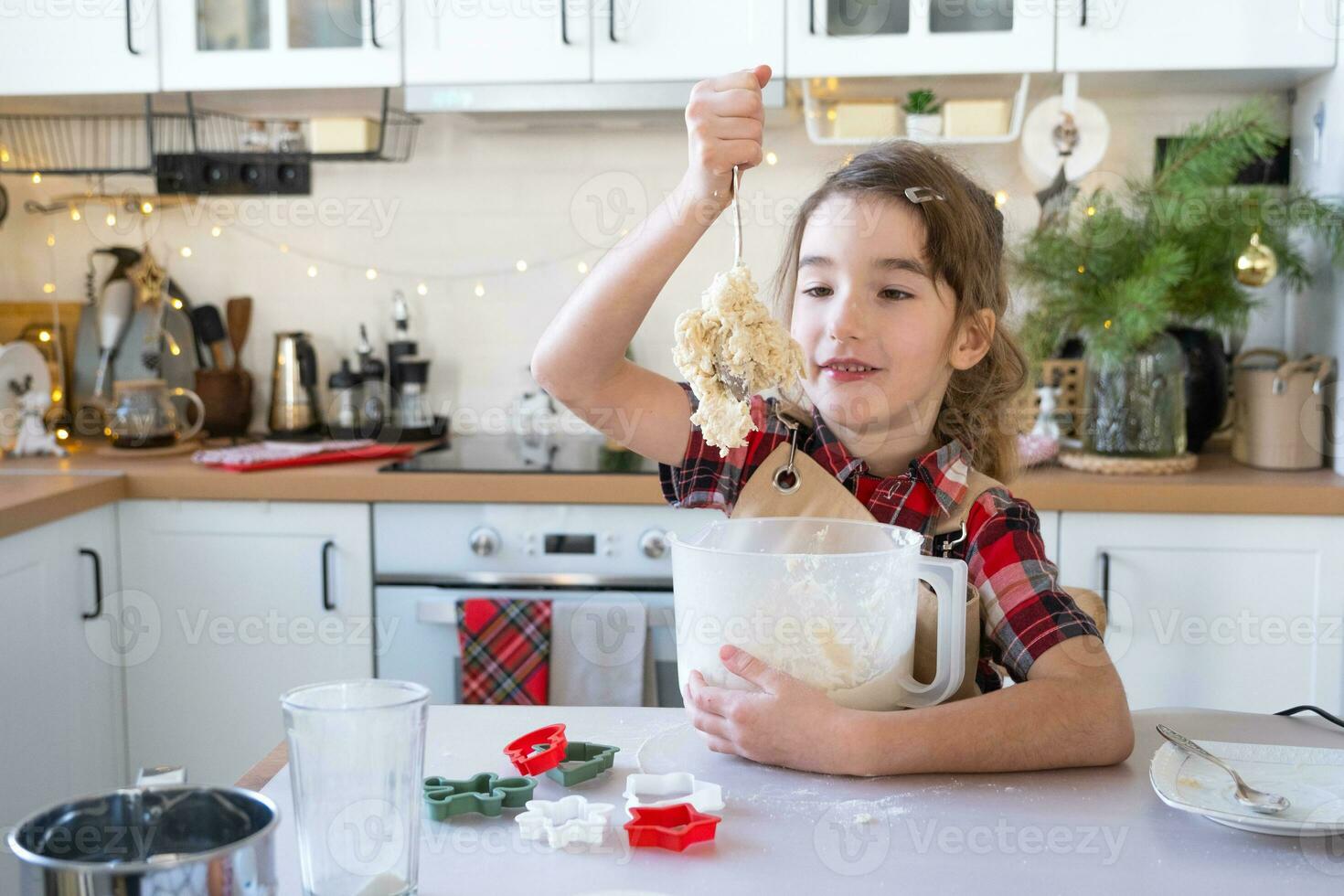 figlia apprendimento per cucinare aiuta nel il bianca cucina impastare il Impasto nel il ciotola per Pan di zenzero e biscotti per Natale e nuovo anno. mettere il ingredienti foto