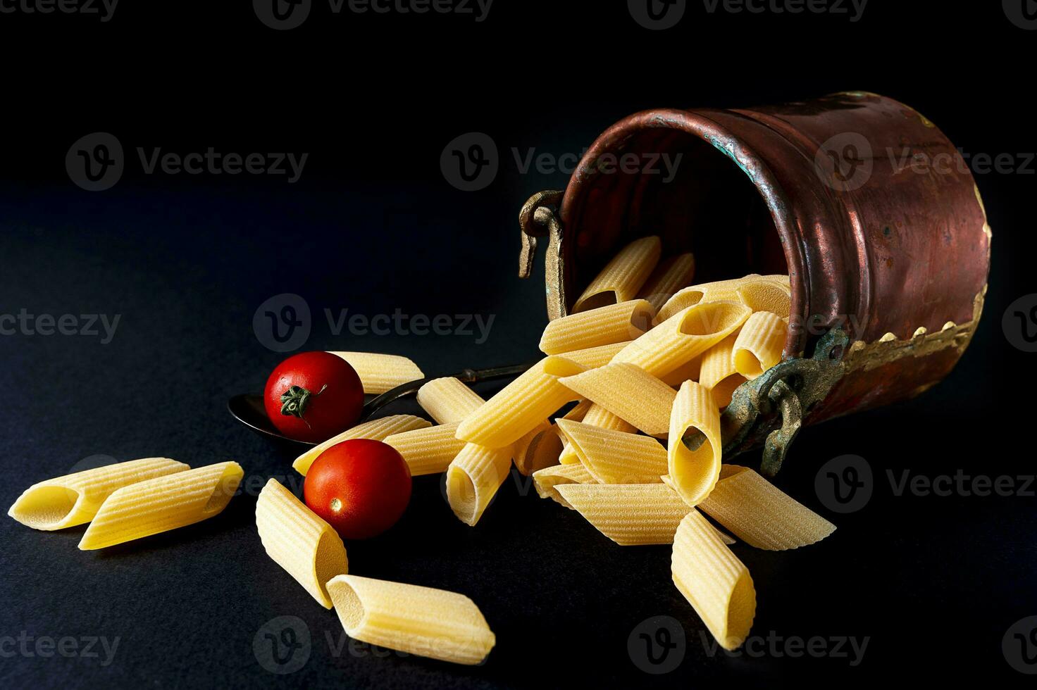 fresco penne rigate maccheroni pasta e ciliegia pomodori nel un' rame baccello foto