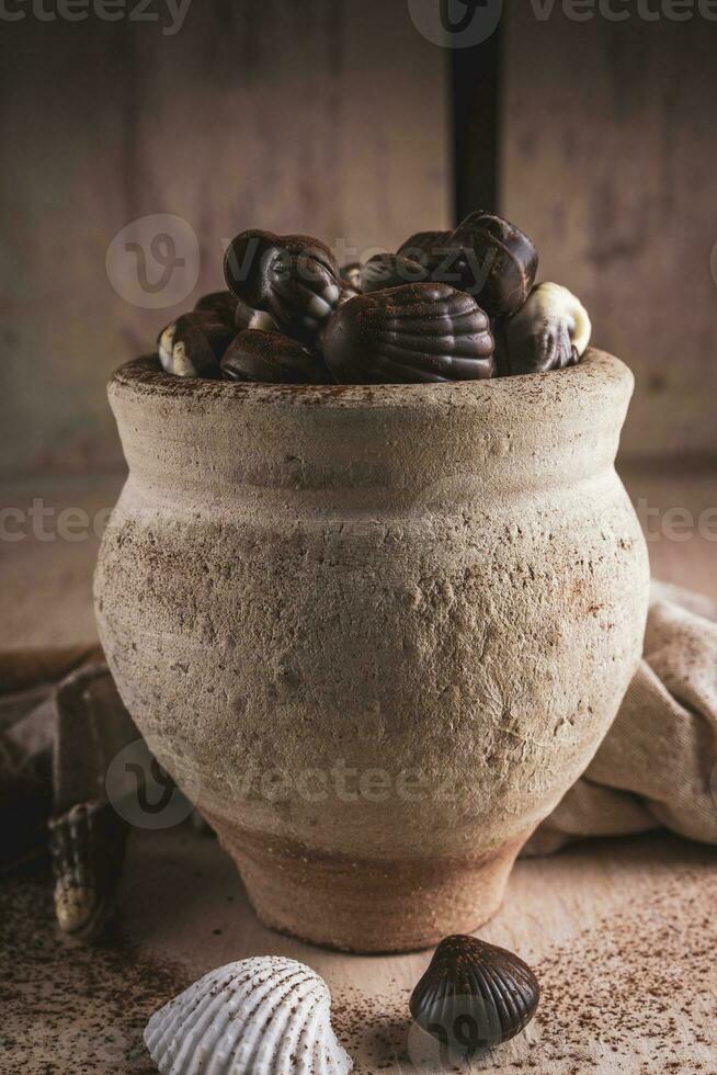 conchiglia sagomato cioccolatini con crema nel un' argilla vaso foto