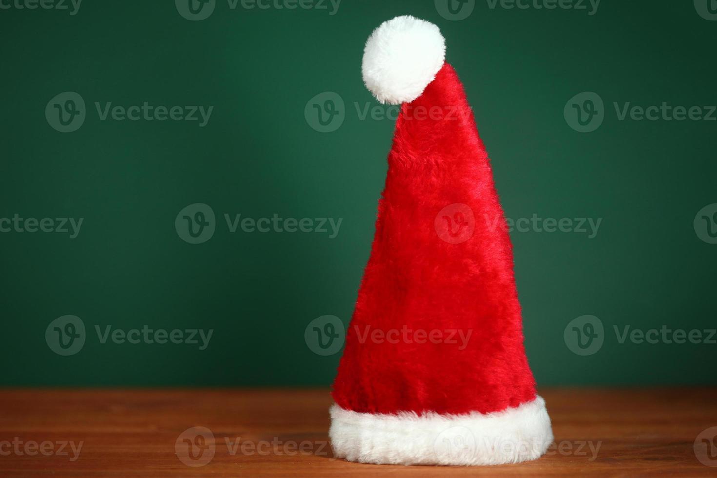 cappello rosso di babbo natale con copia spazio su sfondo verde e legno foto