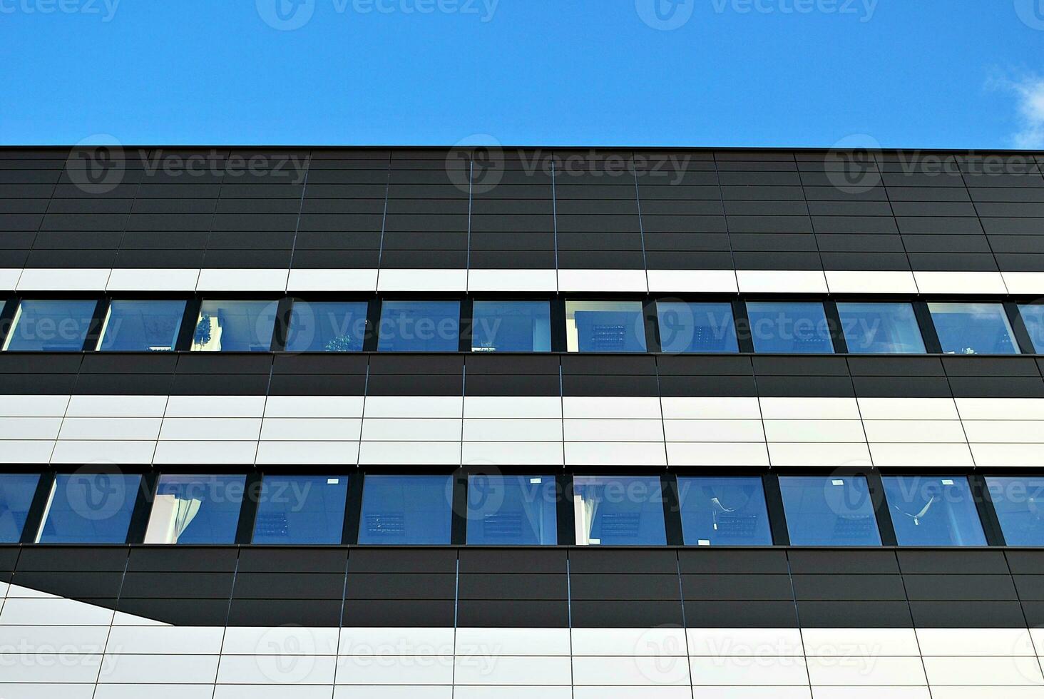 astratto avvicinamento di il rivestito di vetro facciata di un' moderno edificio coperto nel riflessivo piatto bicchiere. architettura astratto sfondo. bicchiere parete e facciata dettaglio. foto