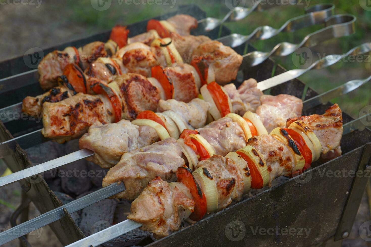 grigliato pezzi di carne su spiedini, shish kebab con la verdura, cucinando processi su braciere foto
