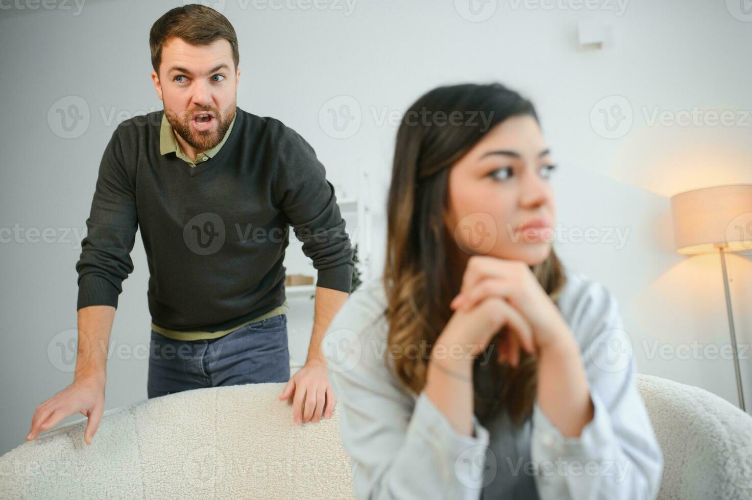 emotivo uomo Esprimere a gesti e urlando a il suo moglie, giovane coppia avendo litigare a casa. domestico abuso concetto foto