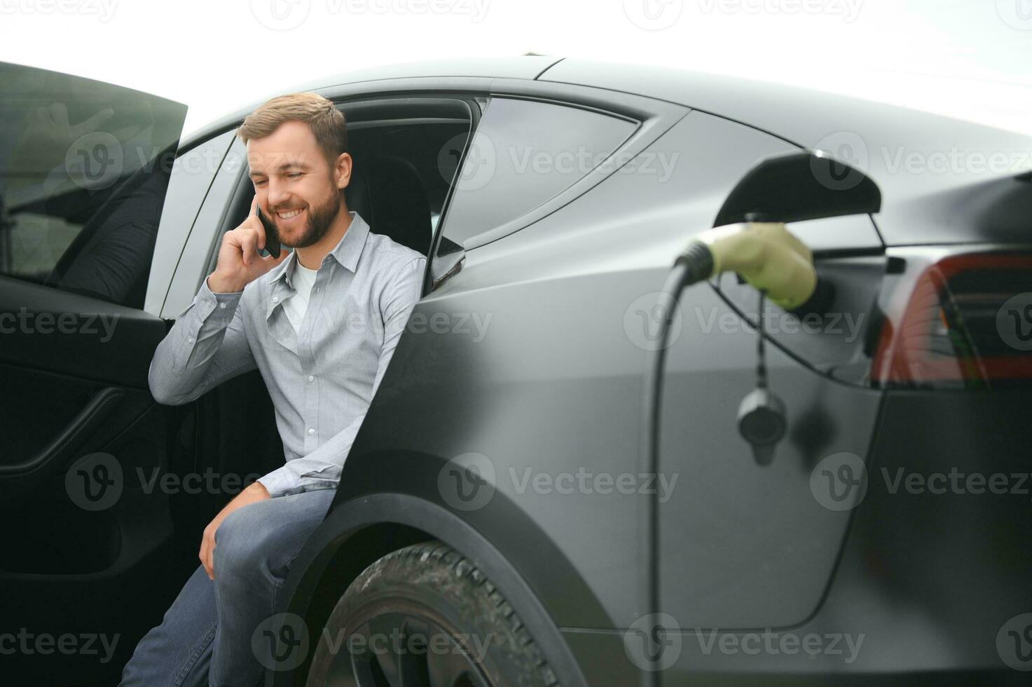 un' uomo addebiti un elettrico auto foto