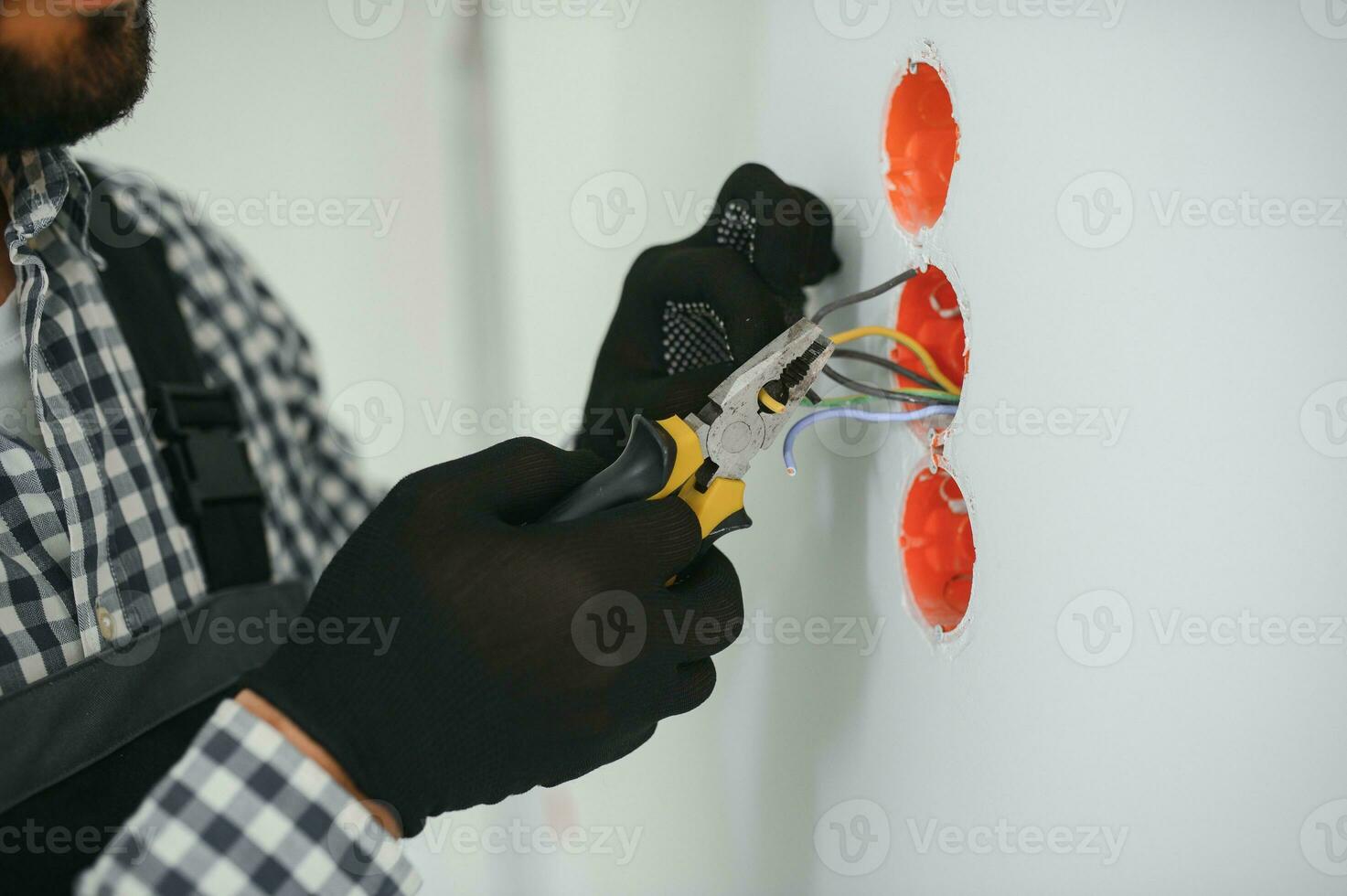 elettricista nel uniforme montaggio elettrico prese su il bianca parete in casa foto