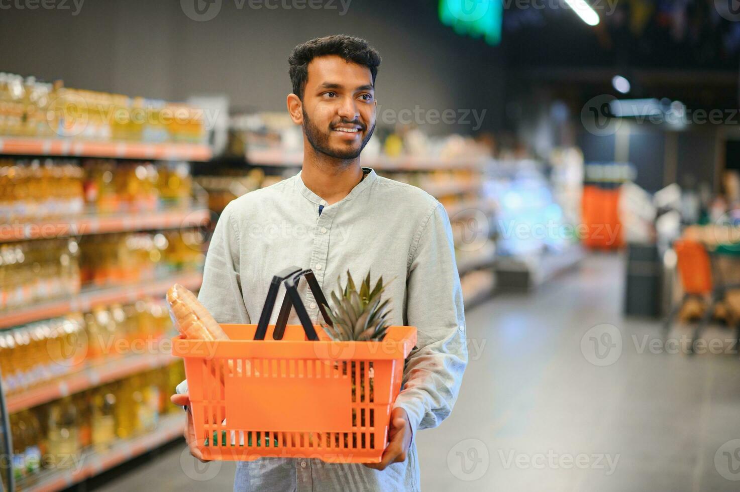 ritratto di contento indiano uomo in piedi nel davanti di il Prodotto contatore nel un' drogheria negozio. uomo acquisto drogheria per casa nel supermercato. foto
