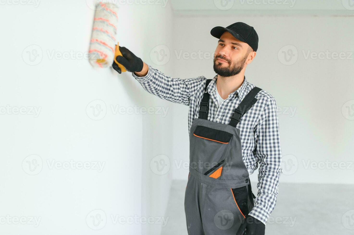 giovane professionale lavoratore nel uniforme in piedi con dipingere rullo. foto