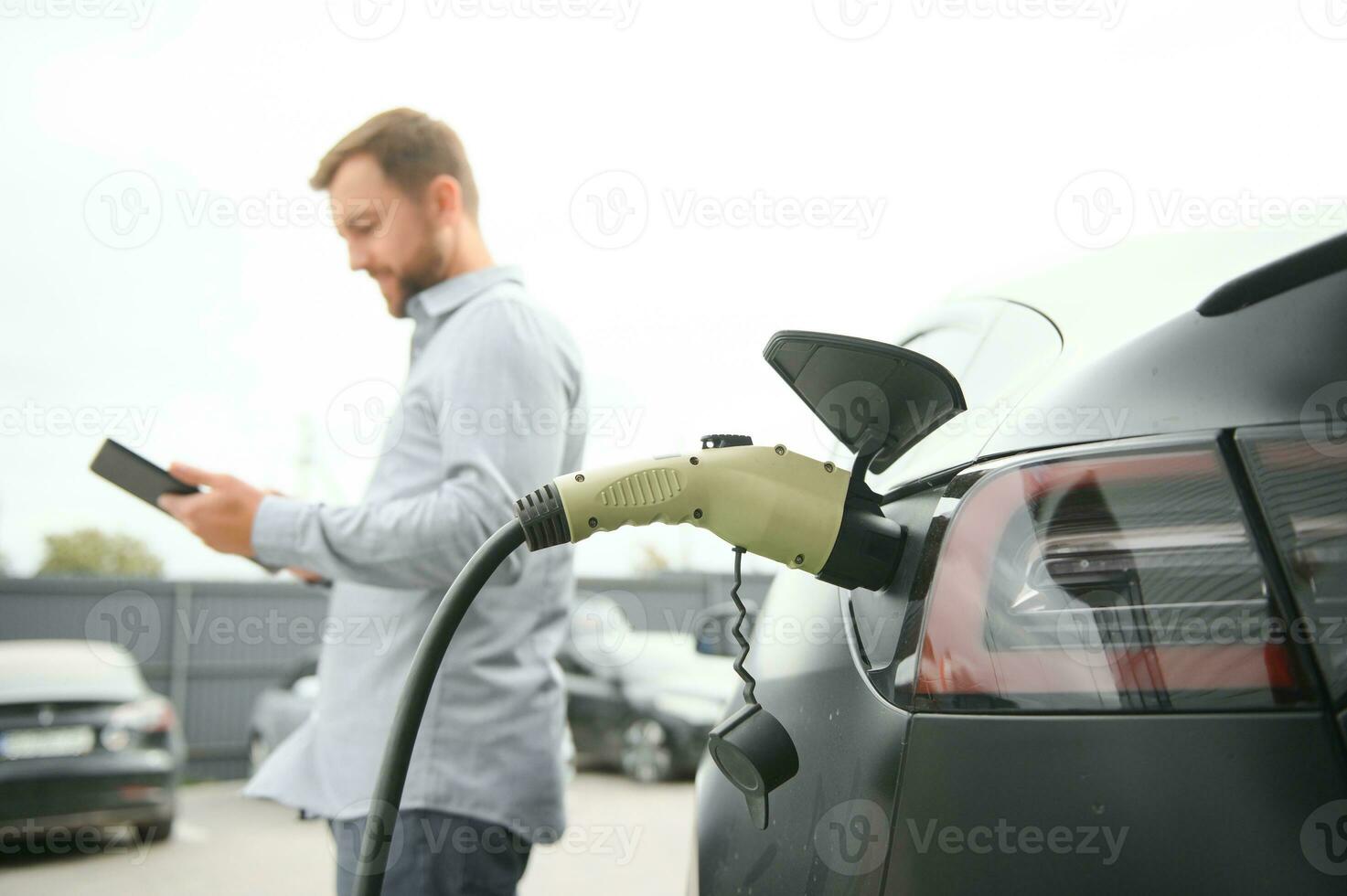 un' uomo addebiti il suo moderno elettrico macchina. il concetto di verde energia foto