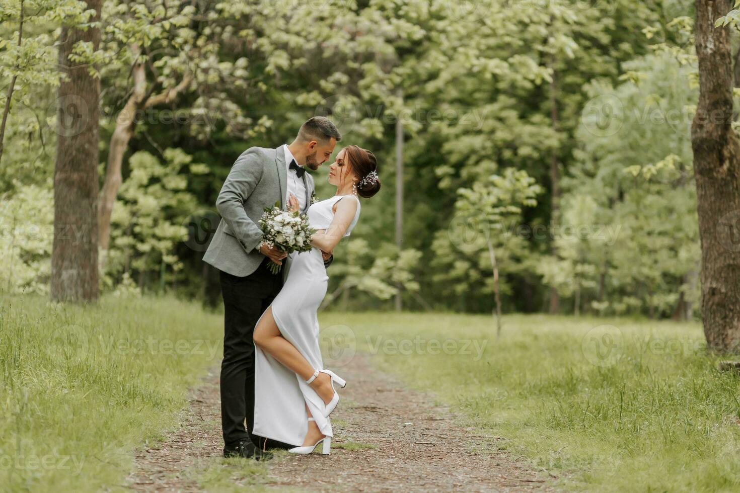 il sposa nel un' bianca sera vestito pose con il sposo con un' bellissimo acconciatura, il sposo delicatamente impacchi il sposa e Leans contro suo. ritratto foto