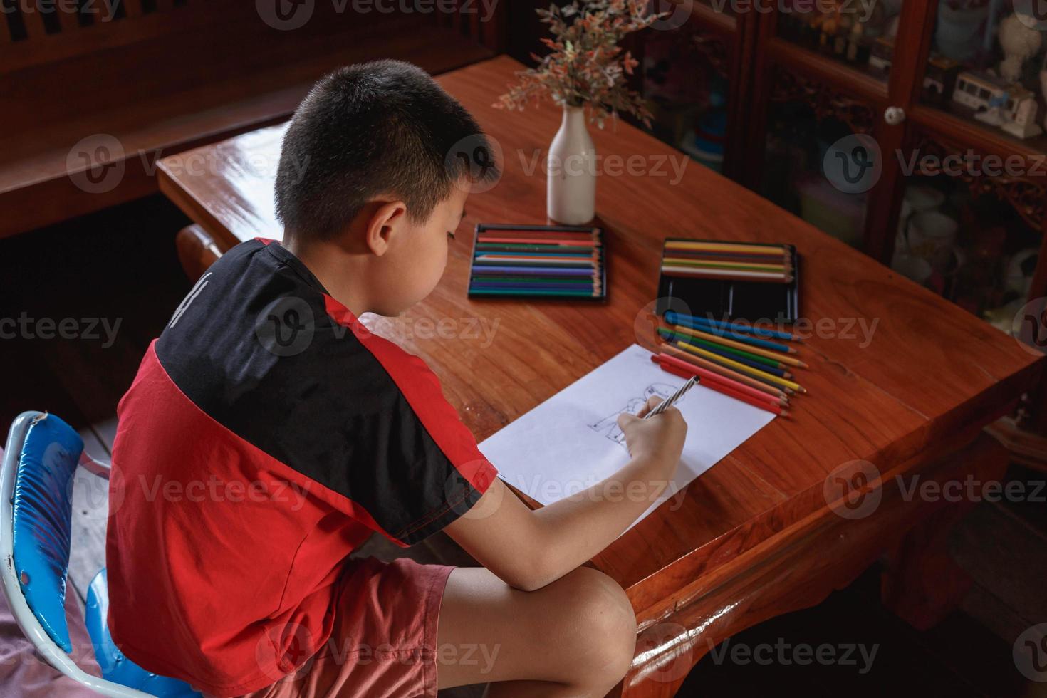 un ragazzo seduto a casa sua a disegnare e dipingere. foto