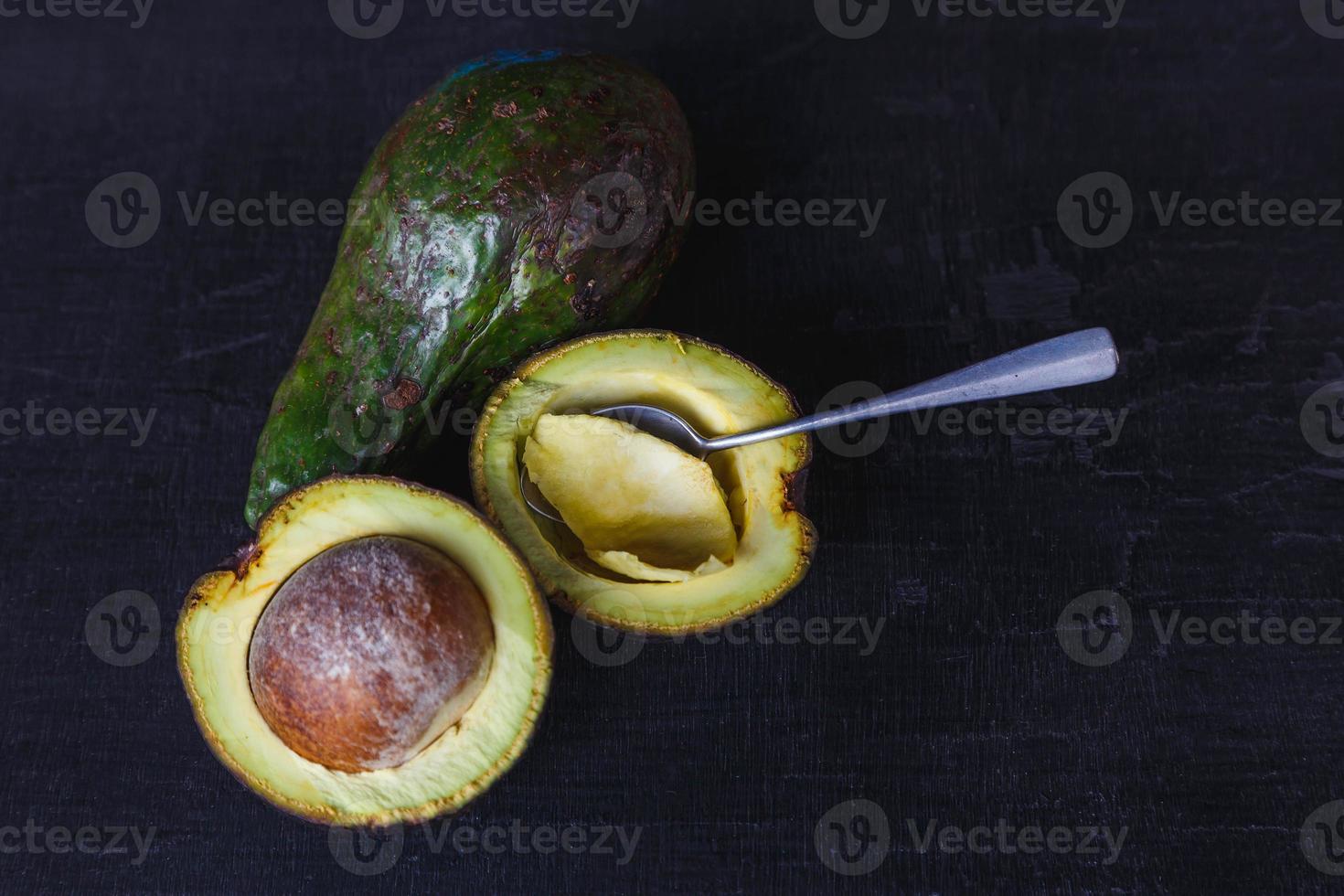 frutto di avocado tagliato a metà su fondo di legno nero foto