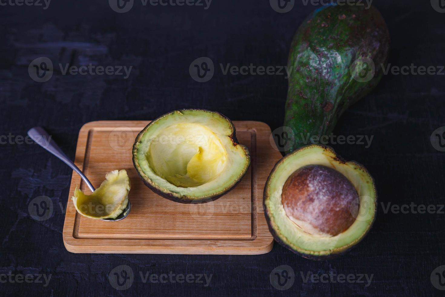 frutto di avocado tagliato a metà su fondo di legno nero foto