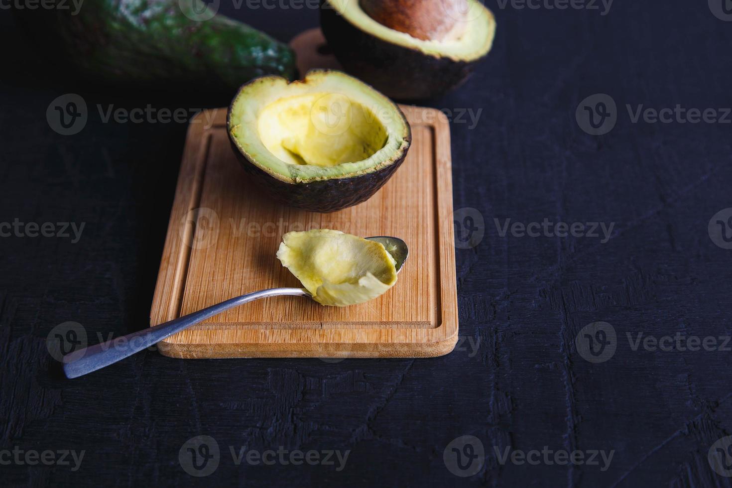 frutto di avocado tagliato a metà su fondo di legno nero foto