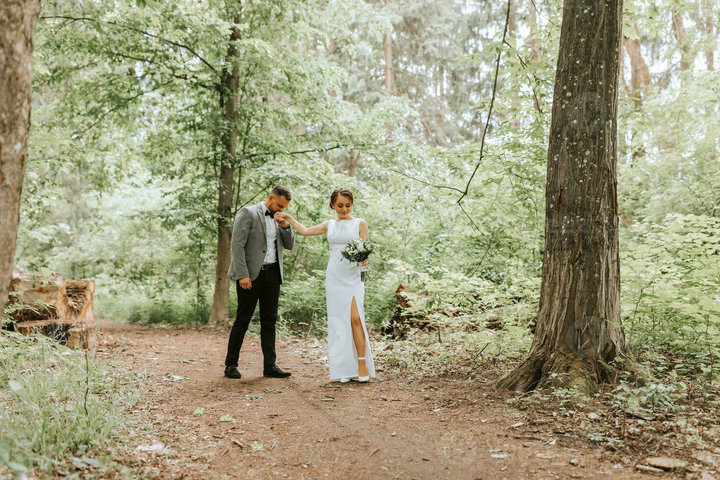 primavera nozze foto di il sposa e sposo. baci il mano. foresta strada fra alto alberi. contento nozze coppia