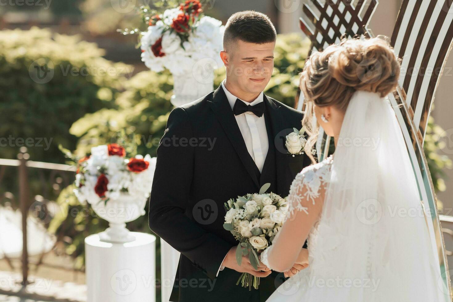 nozze ritratto. nozze cerimonia pittura nel natura. il sposo detiene un' mazzo e sembra a il sposa. bellissimo d'oro arco e fresco fiori foto