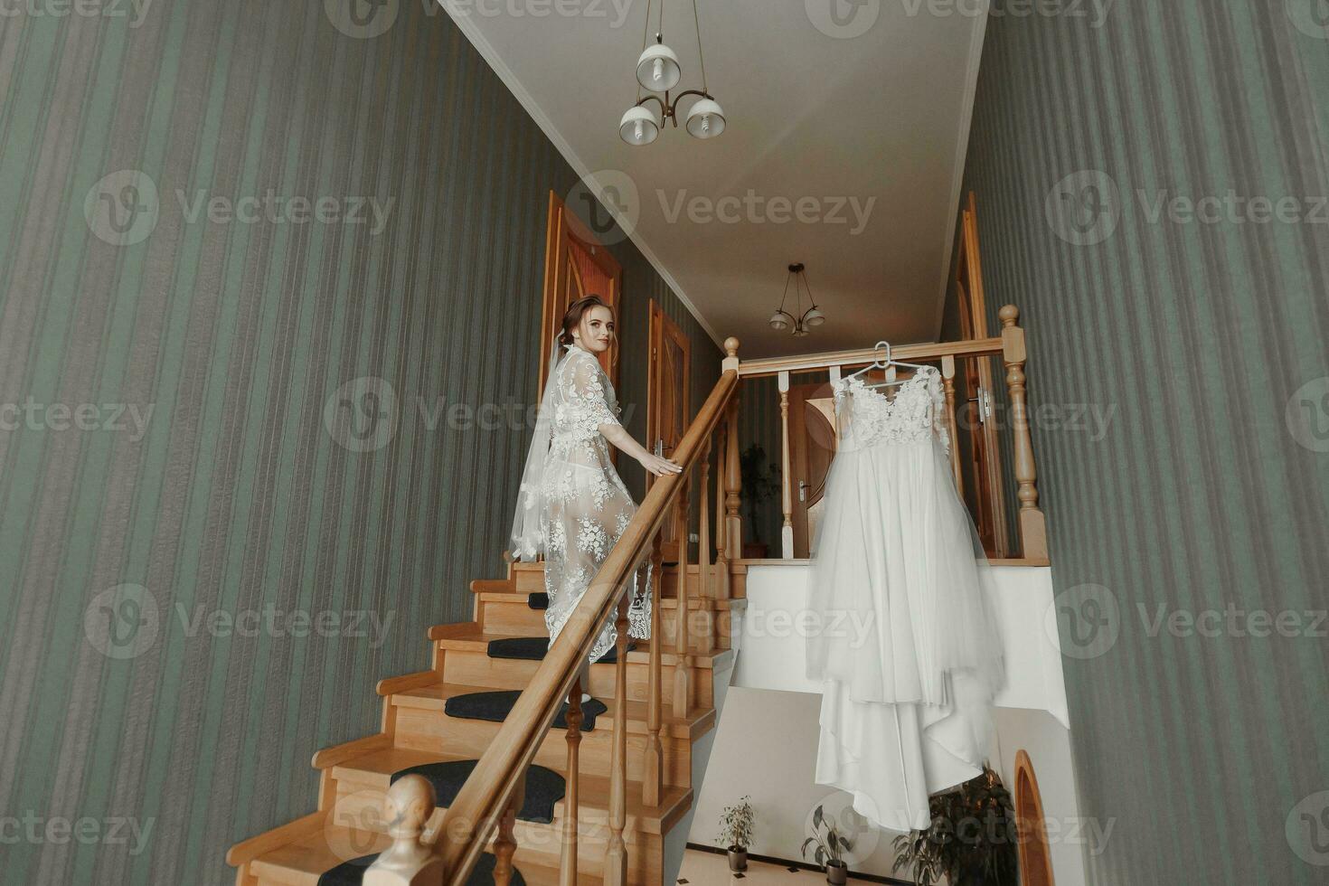 un' delicato nozze vestito si blocca su un' bellissimo ringhiera nel il corridoio di il Casa. il sposa si arrampica il passaggi nel un' delicato trasparente sottoveste. simpatico luce. nozze foto. un' alto qualità foto