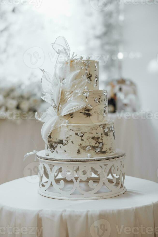bianca nozze torta con fiori. bellissimo fatti in casa a tre livelli nozze torta decorato con bianca orchidee nel un' rustico stile su un' bianca tavolo foto