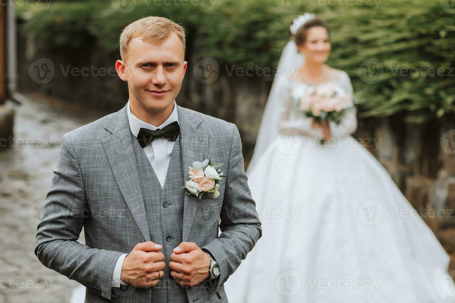 nozze foto nel natura. il sposa è in piedi di il pietra recinto nel un' bellissimo vestire, Tenere un' mazzo di bianca Rose e guardare a lui. il sposo è nel il primo piano