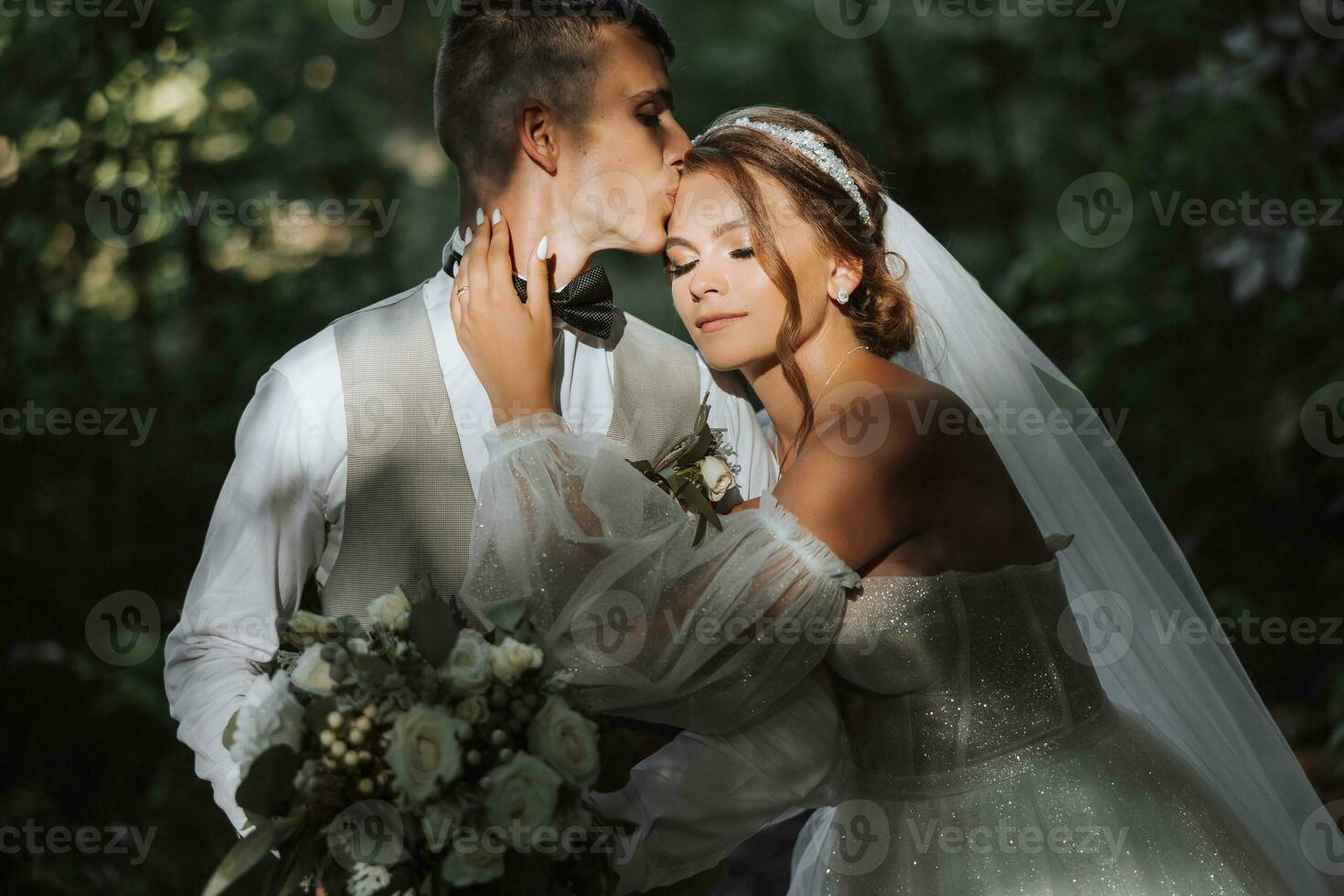 ritratto di un' bellissimo coppia nel amore su il tuo nozze giorno. un' camminare nel il parco nel il luce del sole. sorprendente baci e abbracci di il sposa e sposo con un' mazzo foto