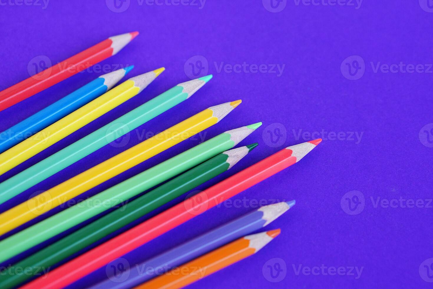 Multi colore matite pastelli su viola sfondo con copia spazio per aggiungendo testo. concetto, formazione scolastica materiali. arte disegno e pittura attrezzatura. foto