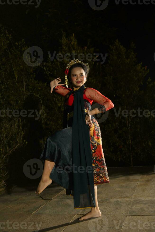 un' giavanese ballerino indossare un' nero scialle e gelsomino su sua testa mentre danza su palcoscenico a notte foto
