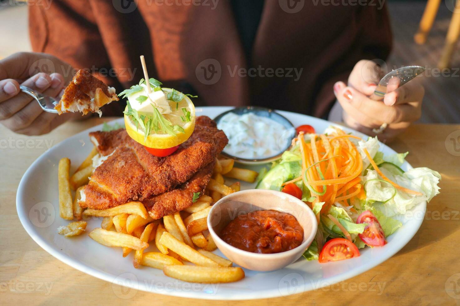 donne mangiare pollo cotoletta servito con Patata patatine fritte foto