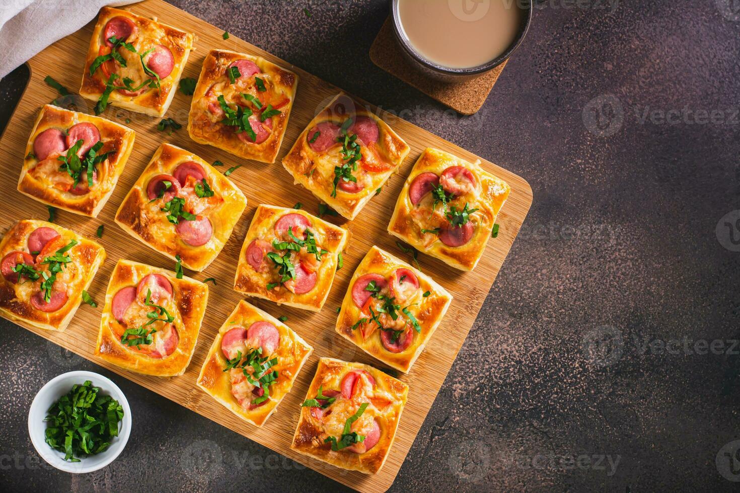 mini Pizza con salsicce, pomodori, formaggio e erbe aromatiche su un' di legno tavola su il tavolo superiore Visualizza foto
