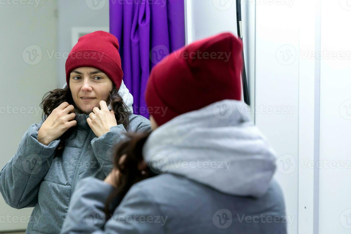 di mezza età donna provando su giacca e cappello nel adattamento camera di Raccogliere punto foto