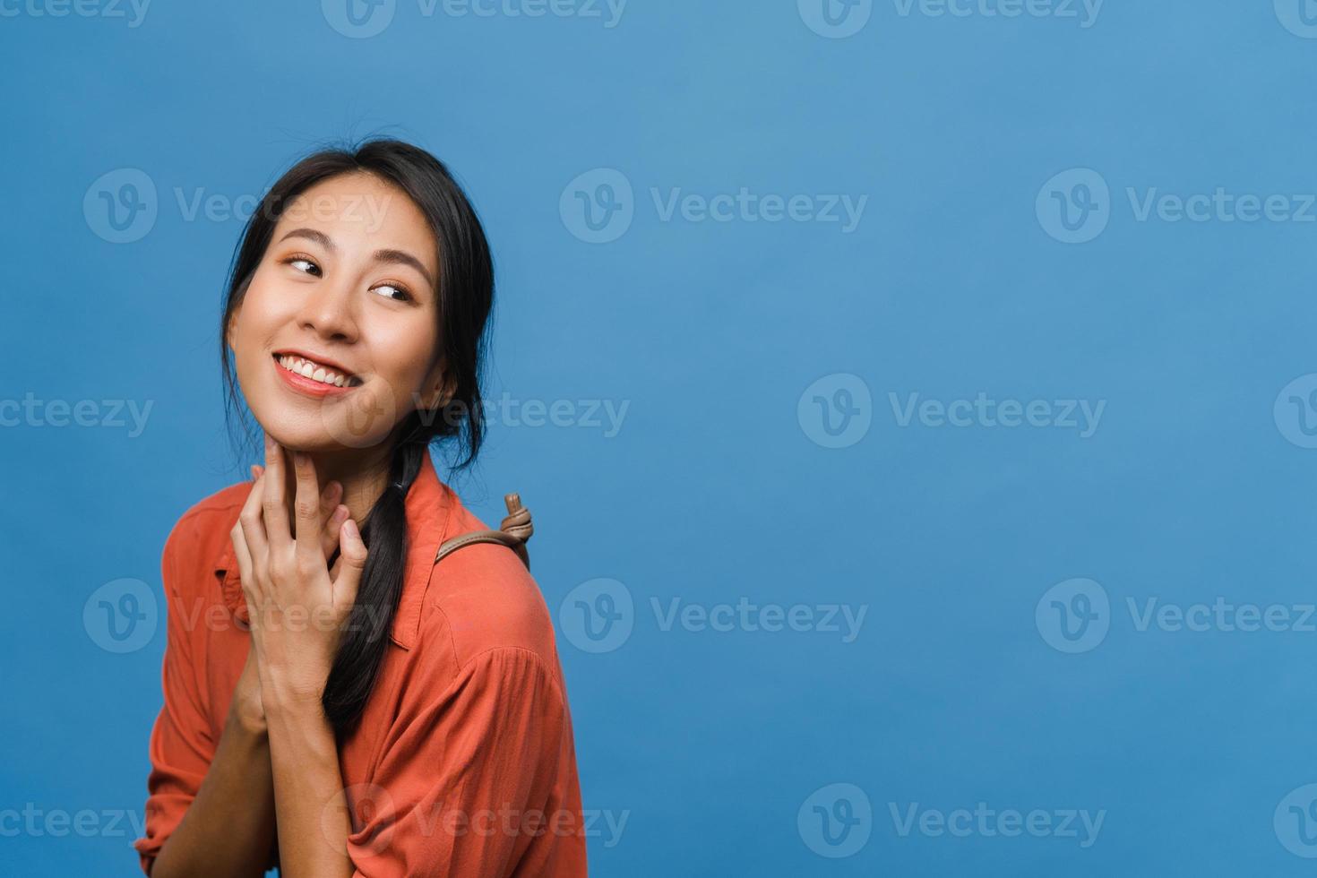 ritratto di giovane donna asiatica con espressione positiva, sorriso ampiamente, vestito con abiti casual su sfondo blu. felice adorabile donna felice esulta successo. concetto di espressione facciale. foto