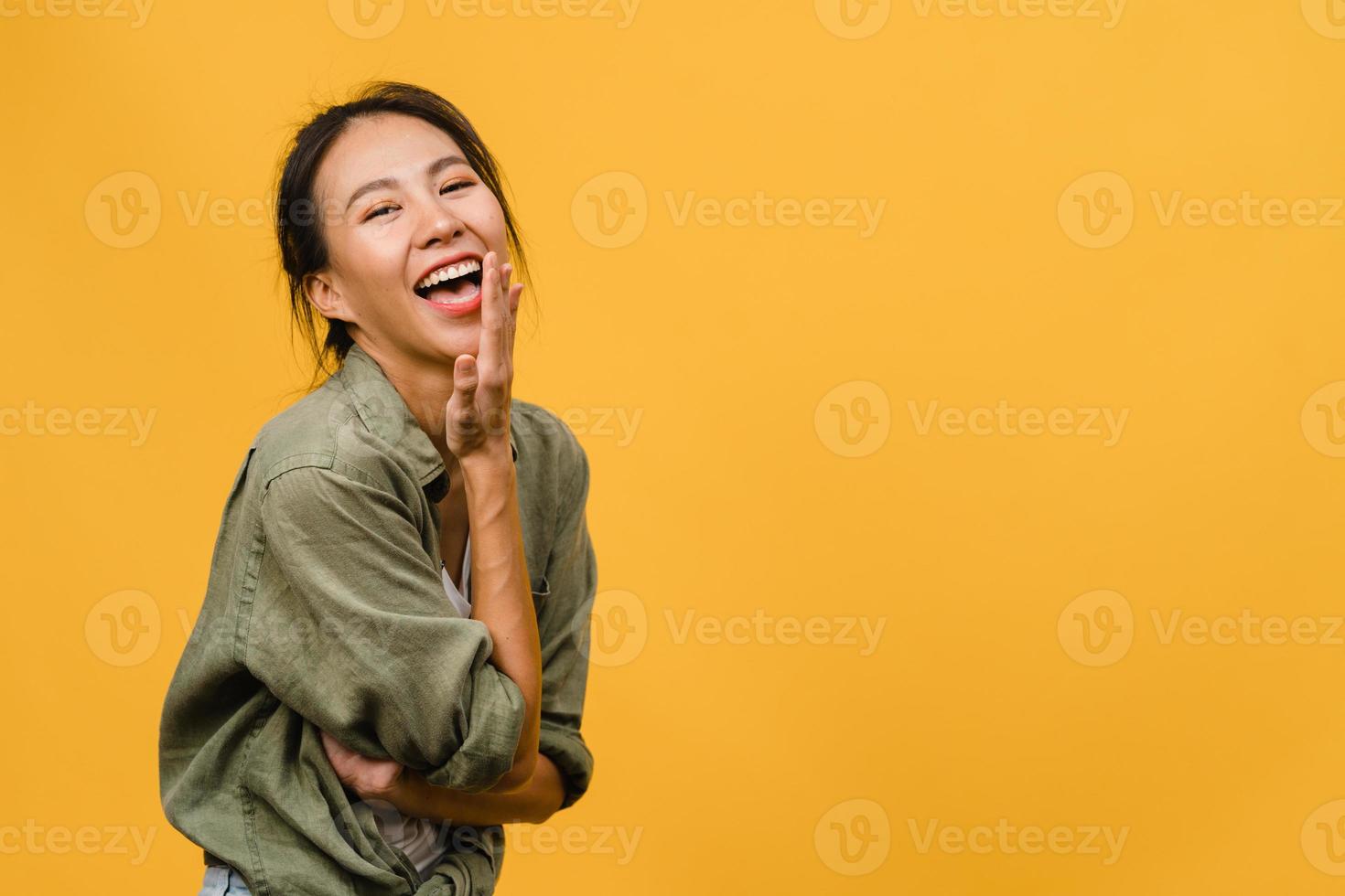 giovane donna asiatica con espressione positiva, sorriso ampiamente, vestita con abiti casual e guardando la telecamera su sfondo giallo. felice adorabile donna felice esulta successo. concetto di espressione facciale. foto