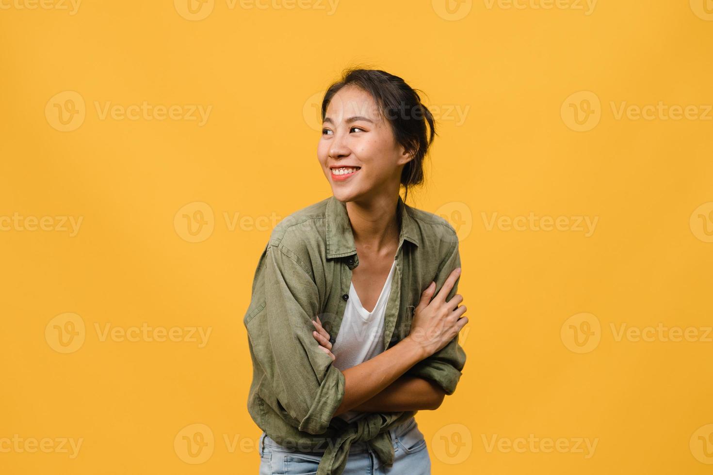 ritratto di giovane donna asiatica con espressione positiva, braccio incrociato, sorriso ampiamente, vestita con un panno casual su sfondo giallo. felice adorabile donna felice esulta successo. concetto di espressione facciale. foto