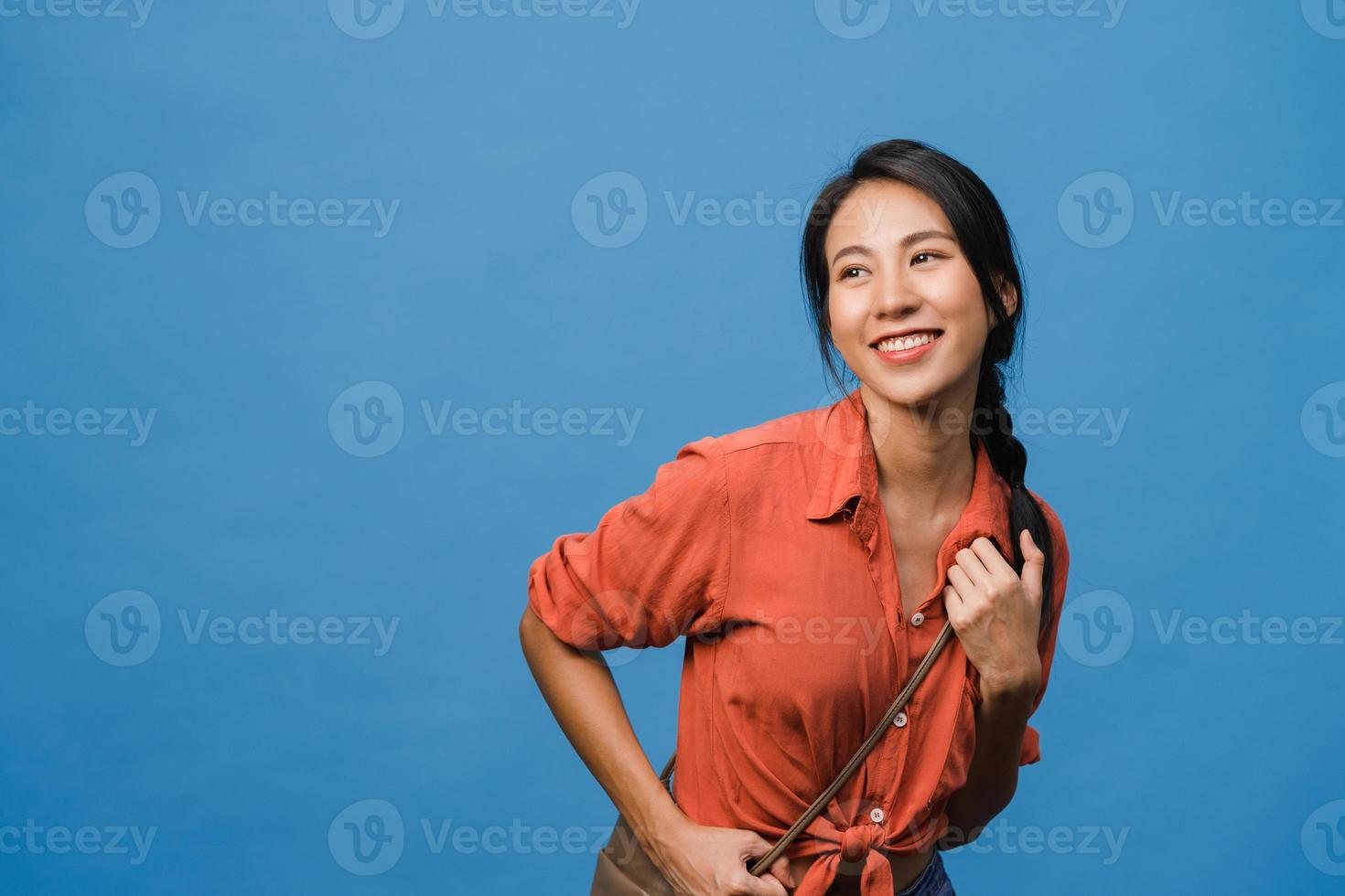 ritratto di giovane donna asiatica con espressione positiva, sorriso ampiamente, vestito con abiti casual su sfondo blu. felice adorabile donna felice esulta successo. concetto di espressione facciale. foto