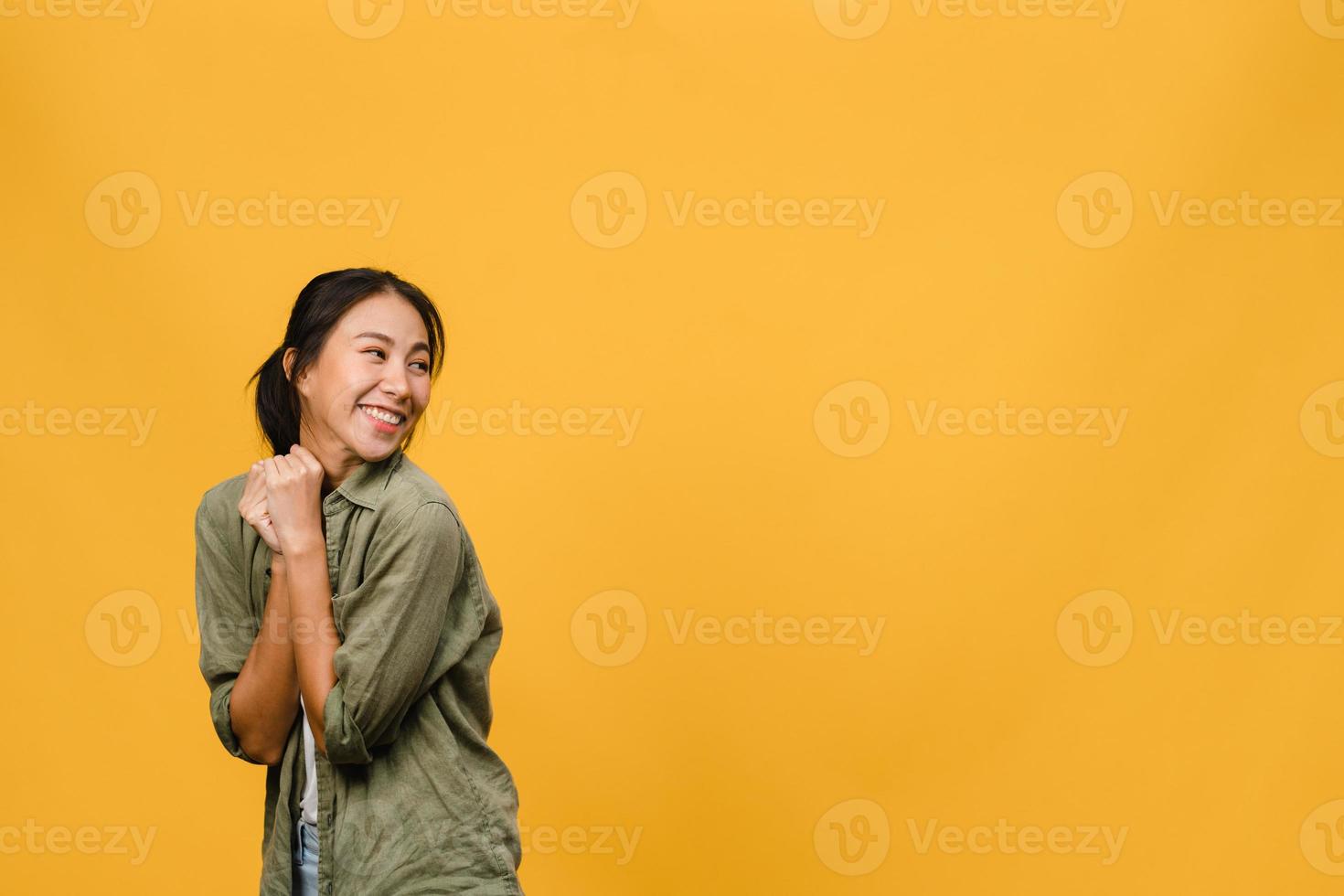 ritratto di giovane donna asiatica con espressione positiva, sorriso ampiamente, vestita con abiti casual su sfondo giallo. felice adorabile donna felice esulta successo. concetto di espressione facciale. foto