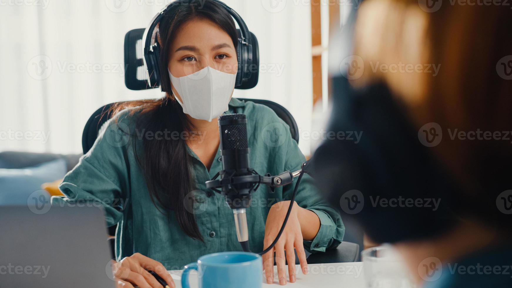 asia ragazza ospite radiofonico registrare podcast utilizzare microfono indossare cuffie intervista contenuto ospite indossare maschera proteggere conversazione virus parlare e ascoltare nella sua stanza. podcast da casa, quarantena coronavirus. foto