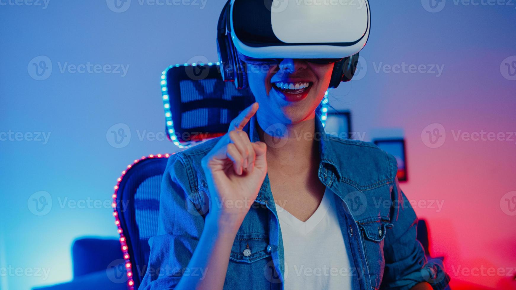 felice ragazza asiatica indossare occhiali per realtà virtuale occhiali auricolare sentirsi a sorpresa programma di gioco reale nel suo studio di casa al neon di notte, giovane donna toccare l'aria l'esperienza vr, attività di quarantena domestica. foto