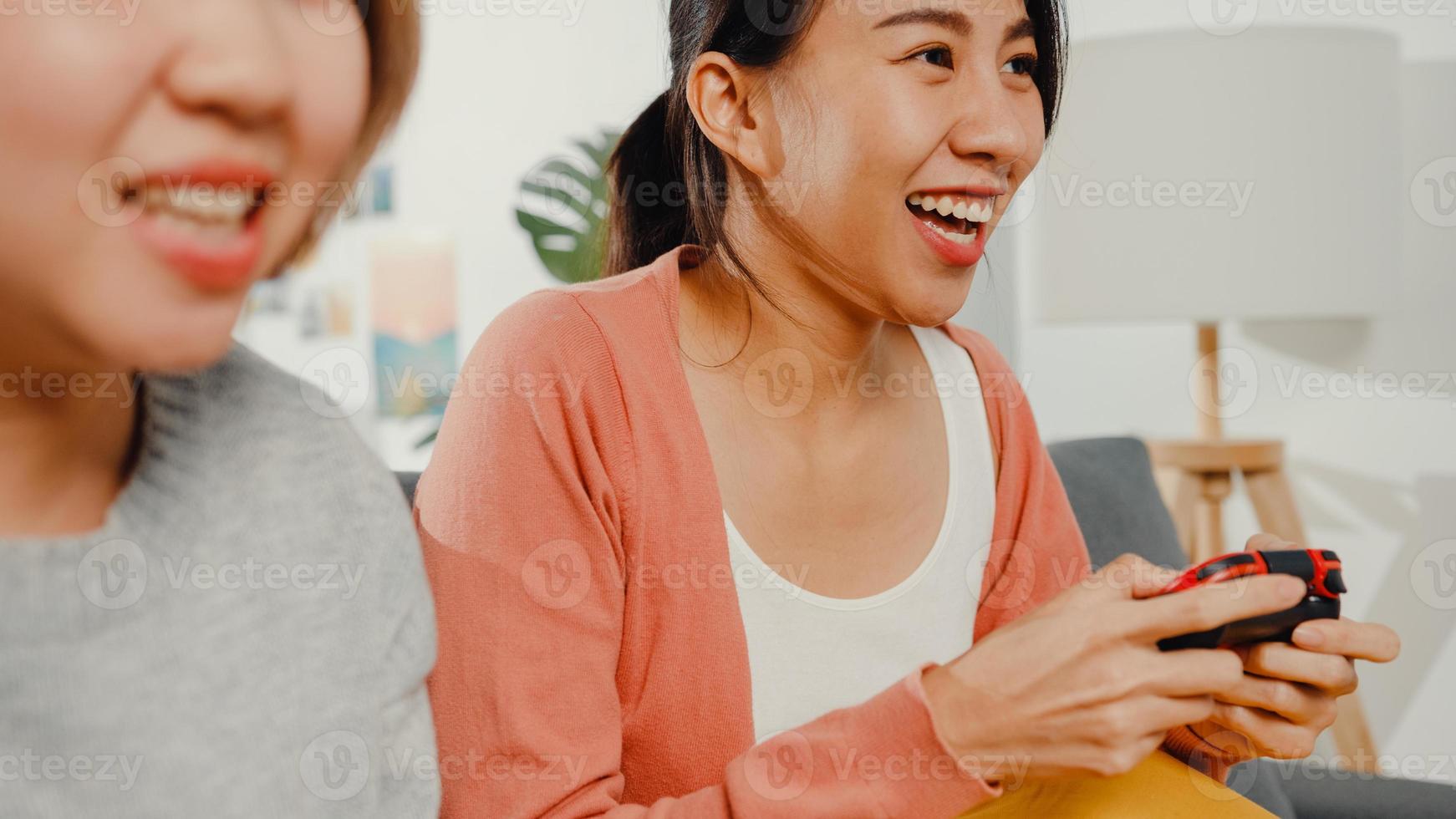 coppia di donne lesbiche lgbtq gioca a un videogioco a casa. giovane donna asiatica che utilizza un controller wireless che ha un momento felice e divertente insieme sul divano nel soggiorno. si divertono molto e festeggiano le vacanze. foto