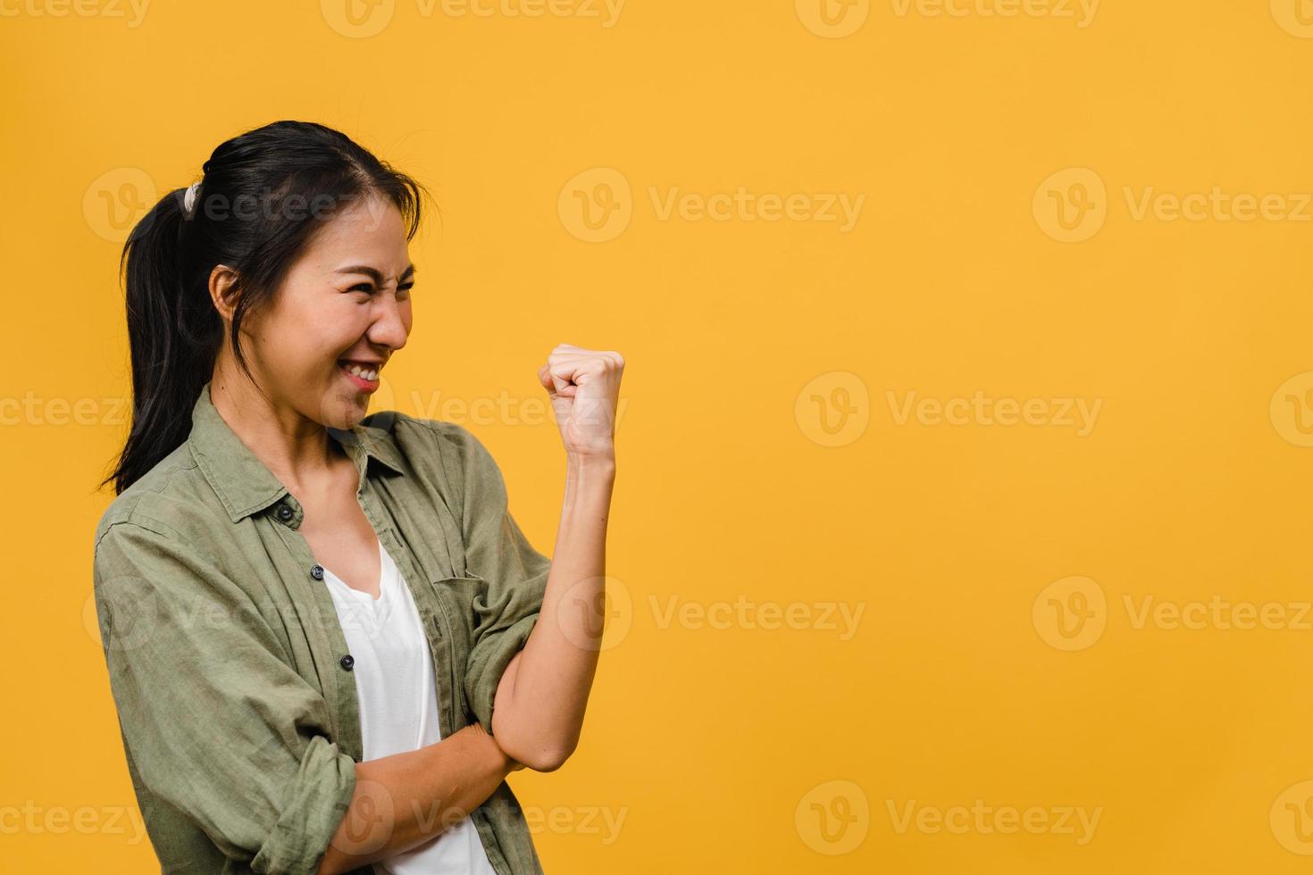 giovane donna asiatica con espressione positiva, gioiosa ed eccitante, vestita di stoffa casual su sfondo giallo con spazio vuoto. felice adorabile donna felice esulta successo. concetto di espressione facciale. foto