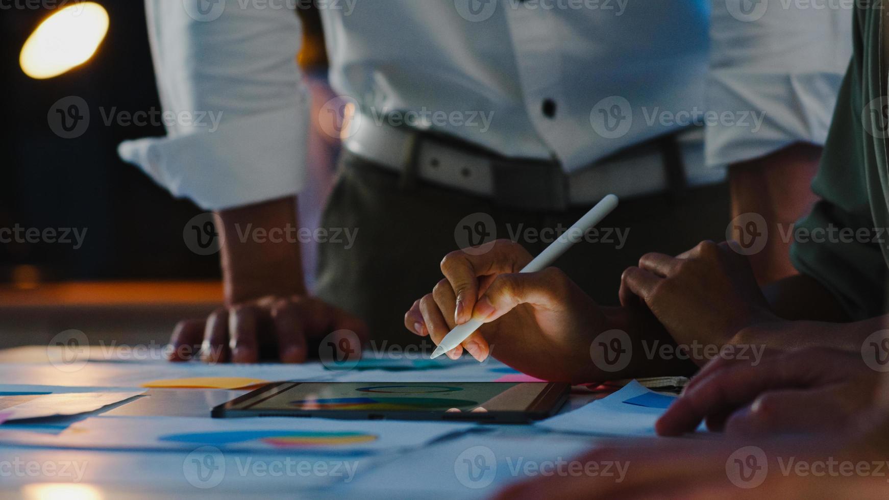 gruppo di giovani creativi asiatici in abbigliamento casual intelligente che discutono di idee per riunioni di brainstorming aziendale progetto di progettazione di software per applicazioni mobili in un moderno ufficio notturno. concetto di lavoro di squadra del collega. foto