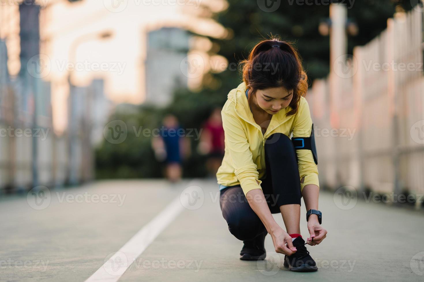 la bella giovane donna atleta asiatica si esercita allacciando i lacci per allenarsi in ambiente urbano. ragazza adolescente giapponese che indossa abiti sportivi sul ponte pedonale al mattino presto. stile di vita sportivo attivo in città. foto