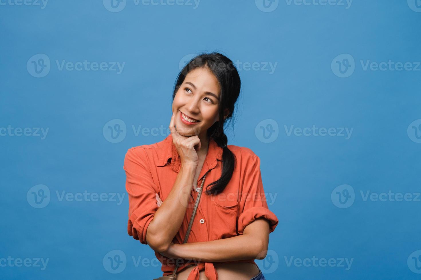 ritratto di giovane donna asiatica con espressione positiva, sorriso ampiamente, vestito con abiti casual su sfondo blu. felice adorabile donna felice esulta successo. concetto di espressione facciale. foto