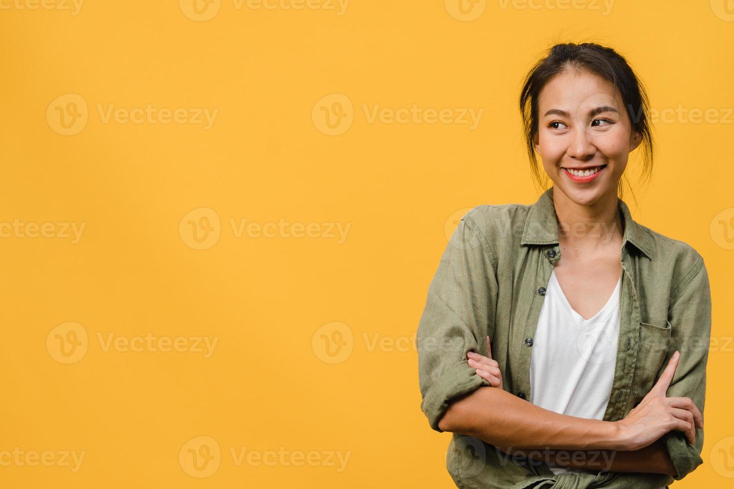 ritratto di giovane donna asiatica con espressione positiva, braccio incrociato, sorriso ampiamente, vestita con un panno casual su sfondo giallo. felice adorabile donna felice esulta successo. concetto di espressione facciale. foto